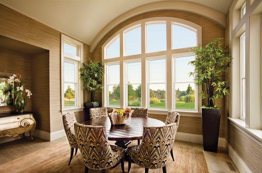 A dining room with large windows and wooden floors.