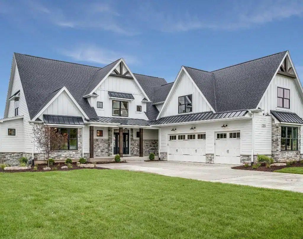 A large white house with large vinyl windows and a green lawn in front of it.