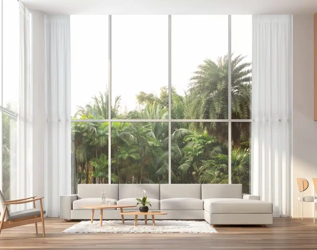 A living room with large windows and white furniture.