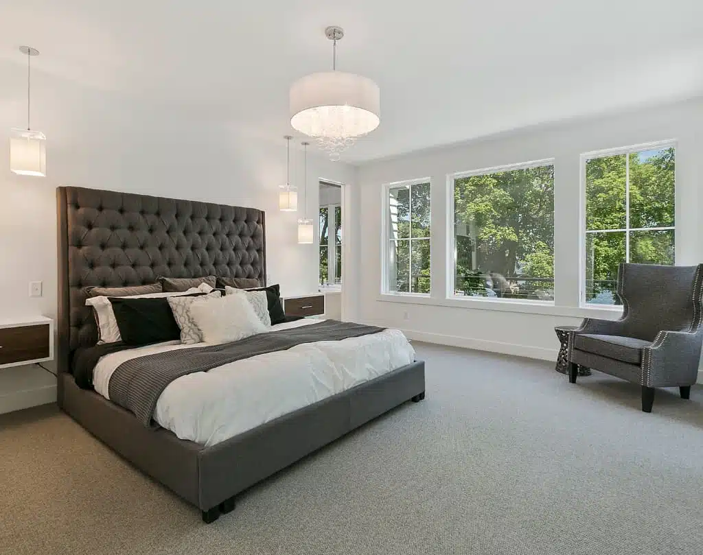 A bedroom with a large bed and two windows.