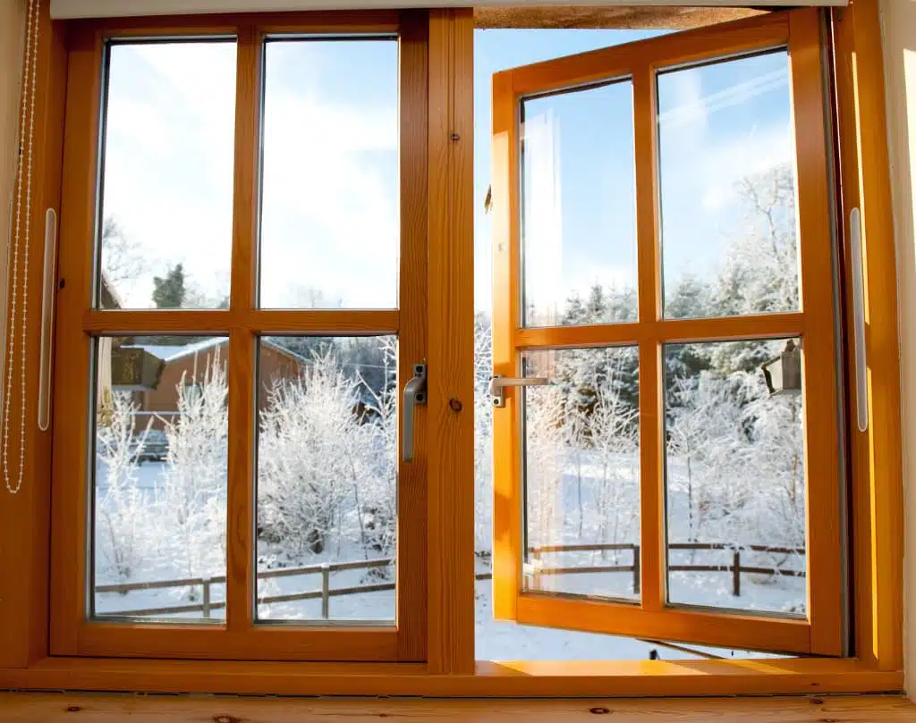 A window with two wooden frames and one of the windows has been opened.